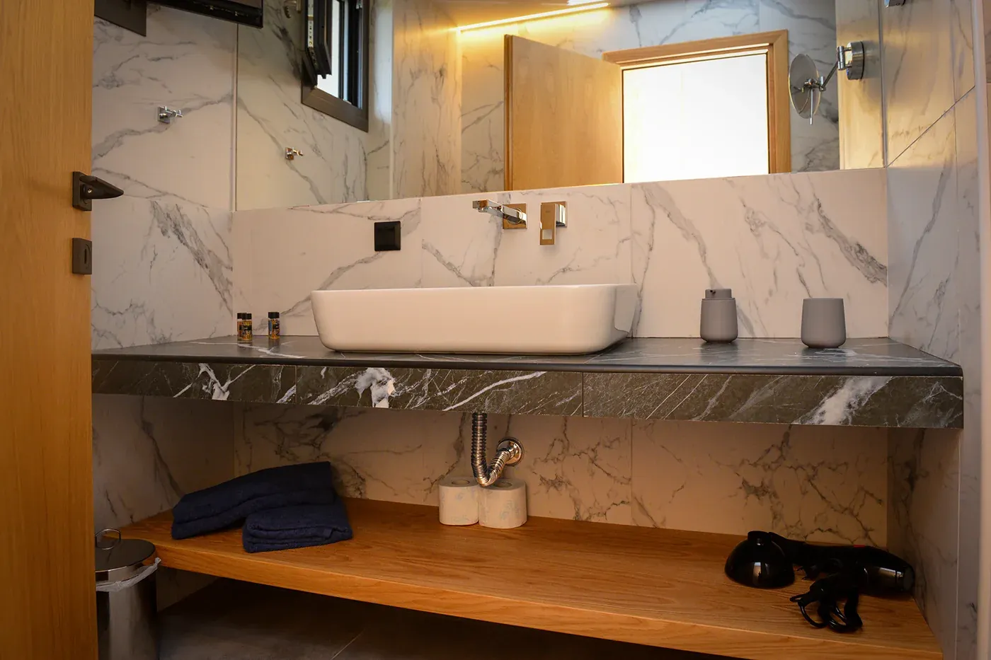 Vessel basin on a dark marble counter above oak shelves