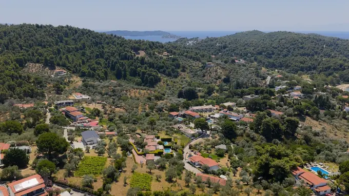Wide aerial view across the green hills of southern Skiathos to the sea