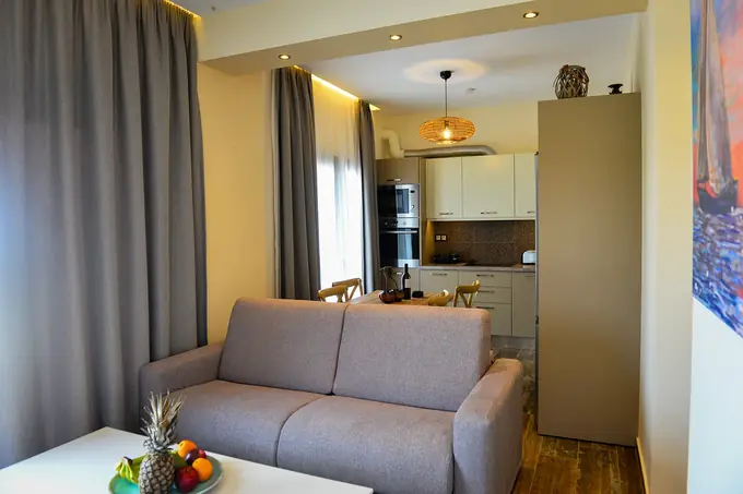 Living room with a sofa and fruit bowl, the kitchen behind