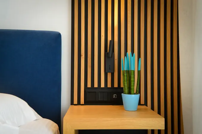 Blue headboard beside a slatted oak wall panel