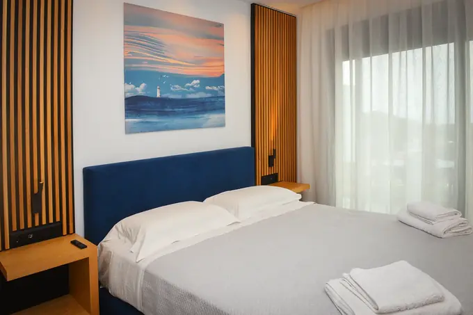 Bedroom with sheer curtains, slatted oak panels and a sunset painting