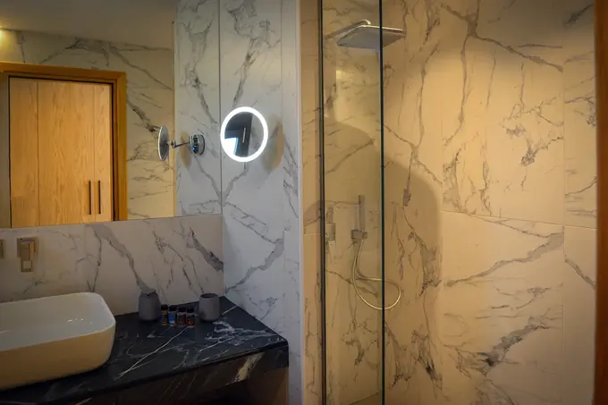 Marble bathroom with a glass shower and a lit mirror