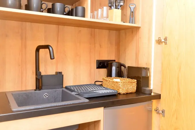 Kitchenette with a black sink, kettle and mugs