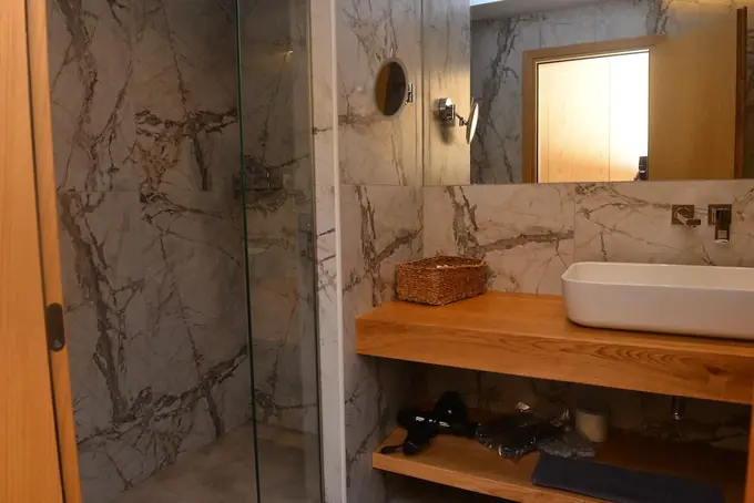 Walk-in shower and oak vanity with a round mirror
