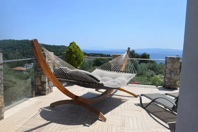 A wooden hammock on the terrace, the sea beyond